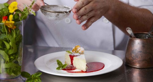 Icing sugar being dusted on a cheesecake