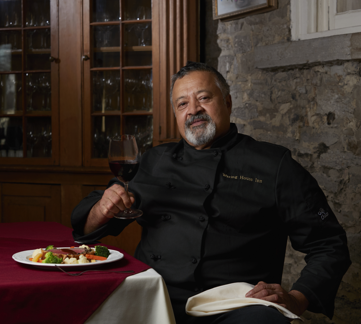 Chef David Correa at a table with wine and food presented. 